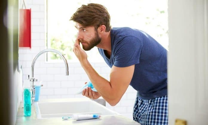 man using beard moisturizer in a bathroom