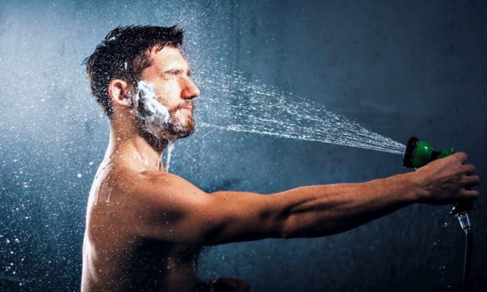 man washing his beard with a garden hose man washing his beard with a garden hose